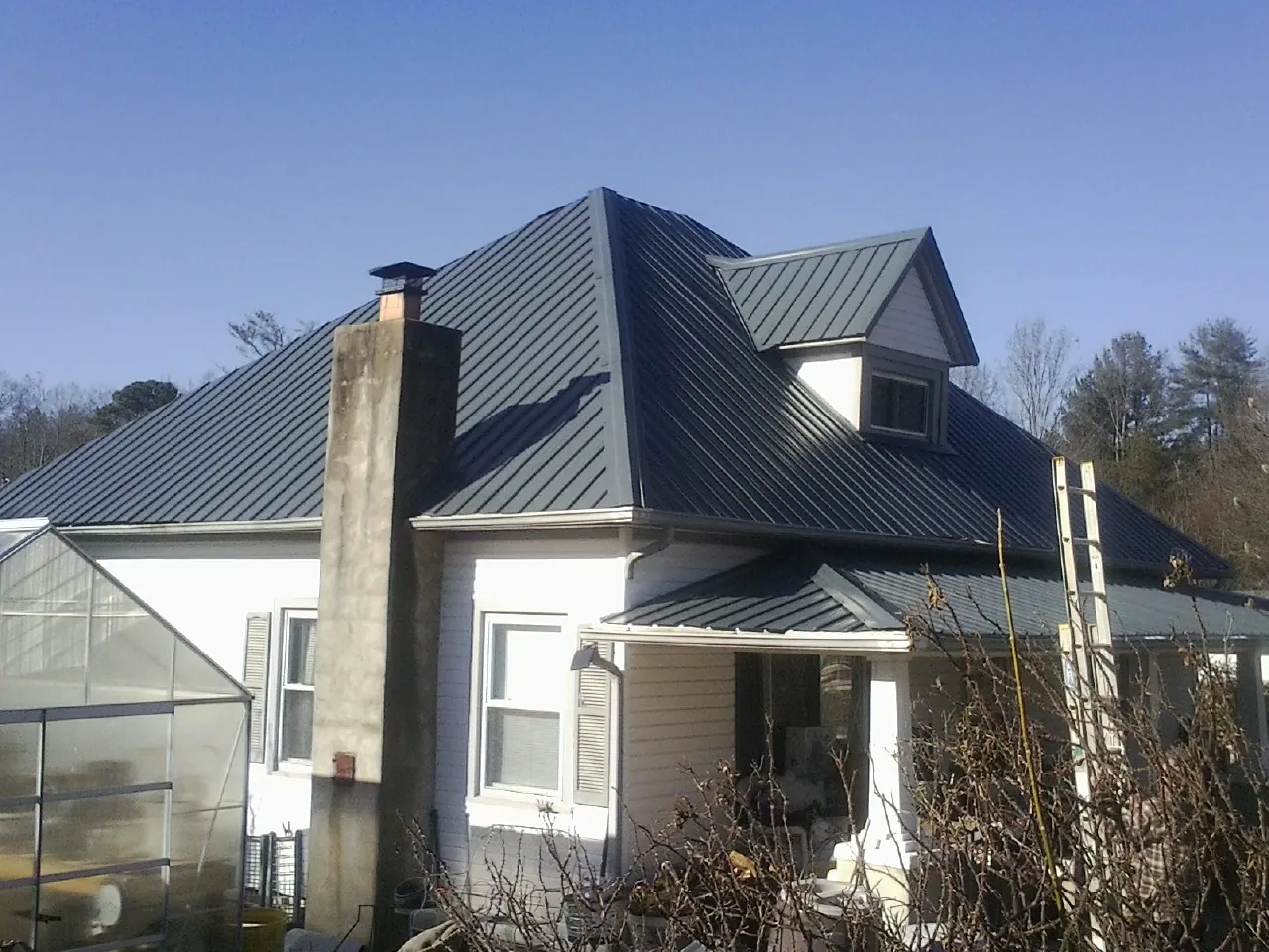 Dark blue standing seam metal roof on a white farmhouse with dormer — Slate & Tile Roof Repair by Roofing Brothers in Gatlinburg