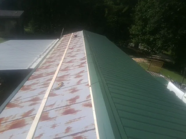 Old rusted panels beside newly installed green metal roofing — Wind Damage Roof Repair by Roofing Brothers in Gatlinburg