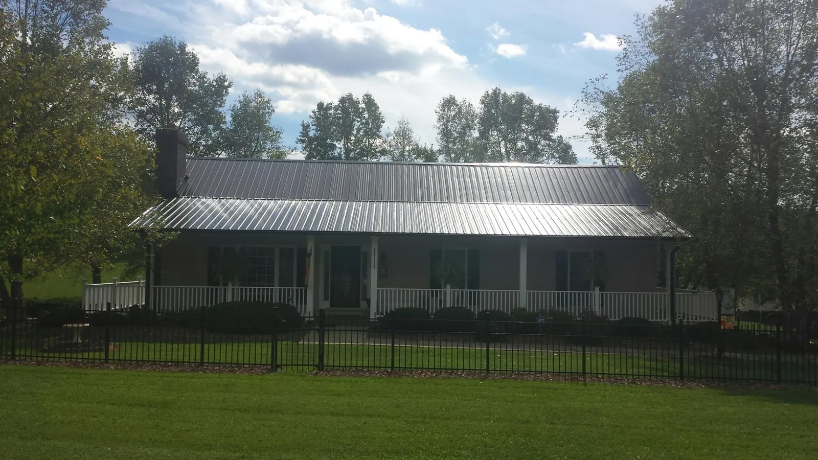Gray metal roof on a brick ranch with a full width front porch — Gutter Guard Installation work by our crew in Gatlinburg