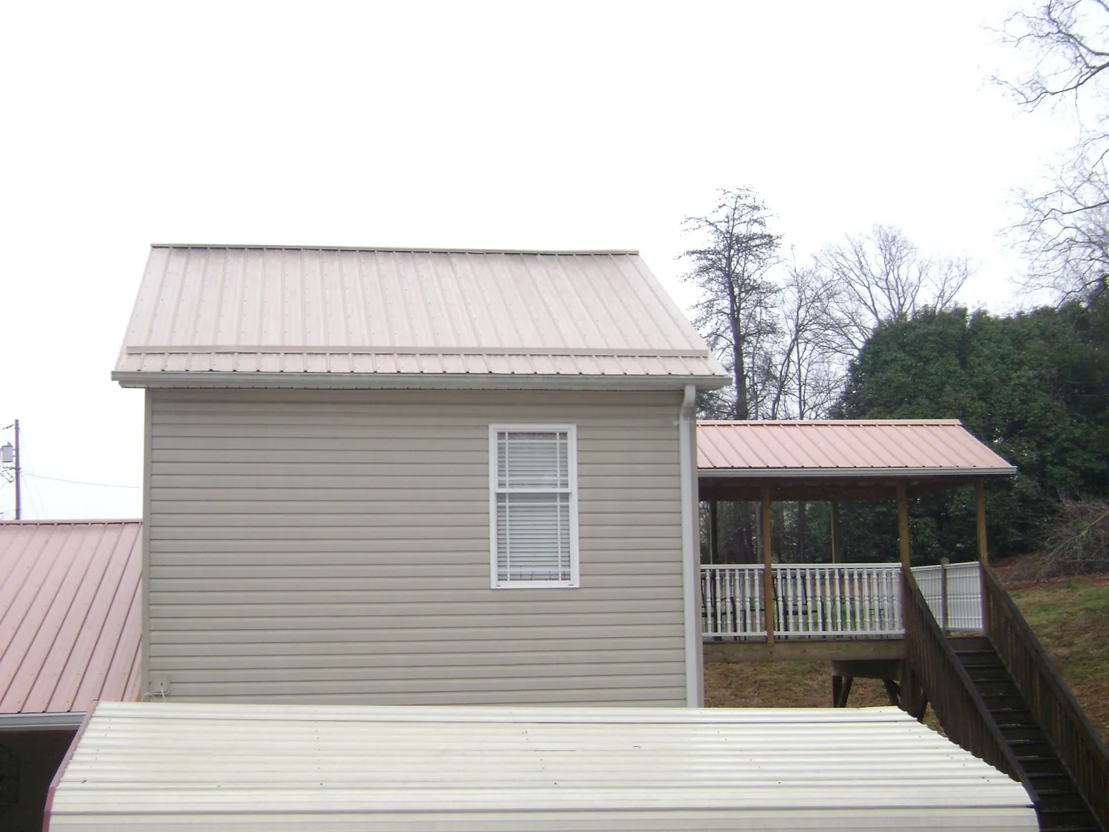 Tan metal roofs on a two story addition and attached porch, from a Roof Replacement job in Gatlinburg