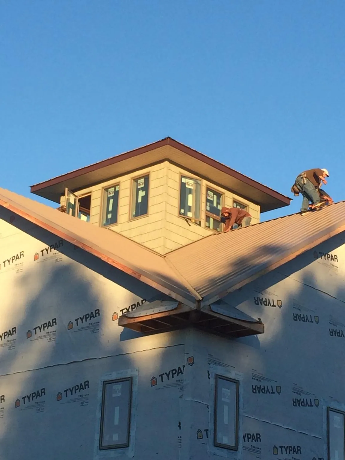 Roofers working around a rooftop cupola on a new metal roof at sunset — Roof Waterproofing in Gatlinburg by Roofing Brothers